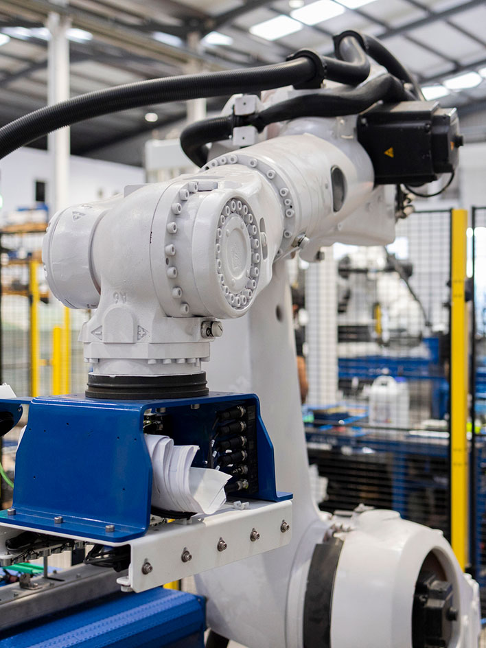 Collaborative robot placing packages in a warehouse with safety barriers.