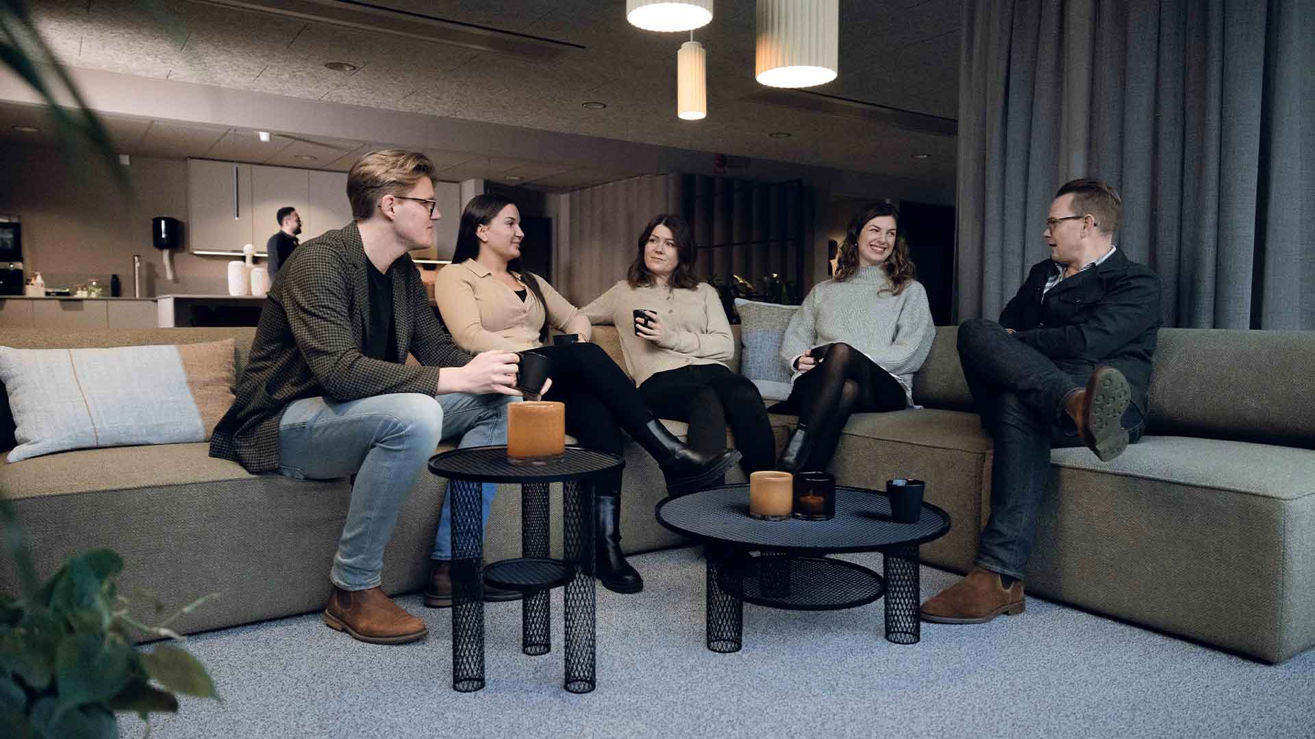 Two men and three women sitting in a sofa and talking