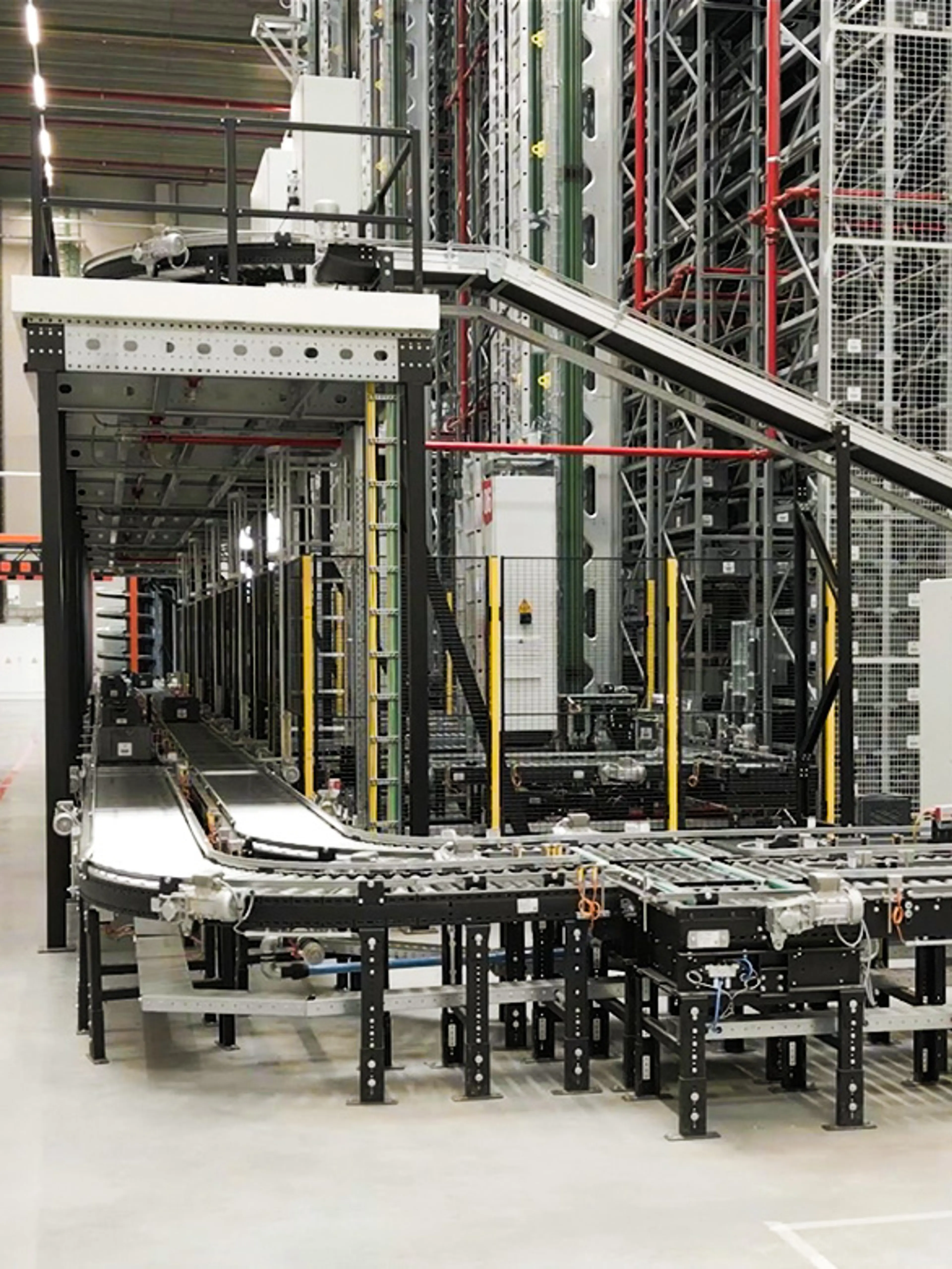 Automated roller and belt conveyor system in a warehouse, used for transporting totes and bins