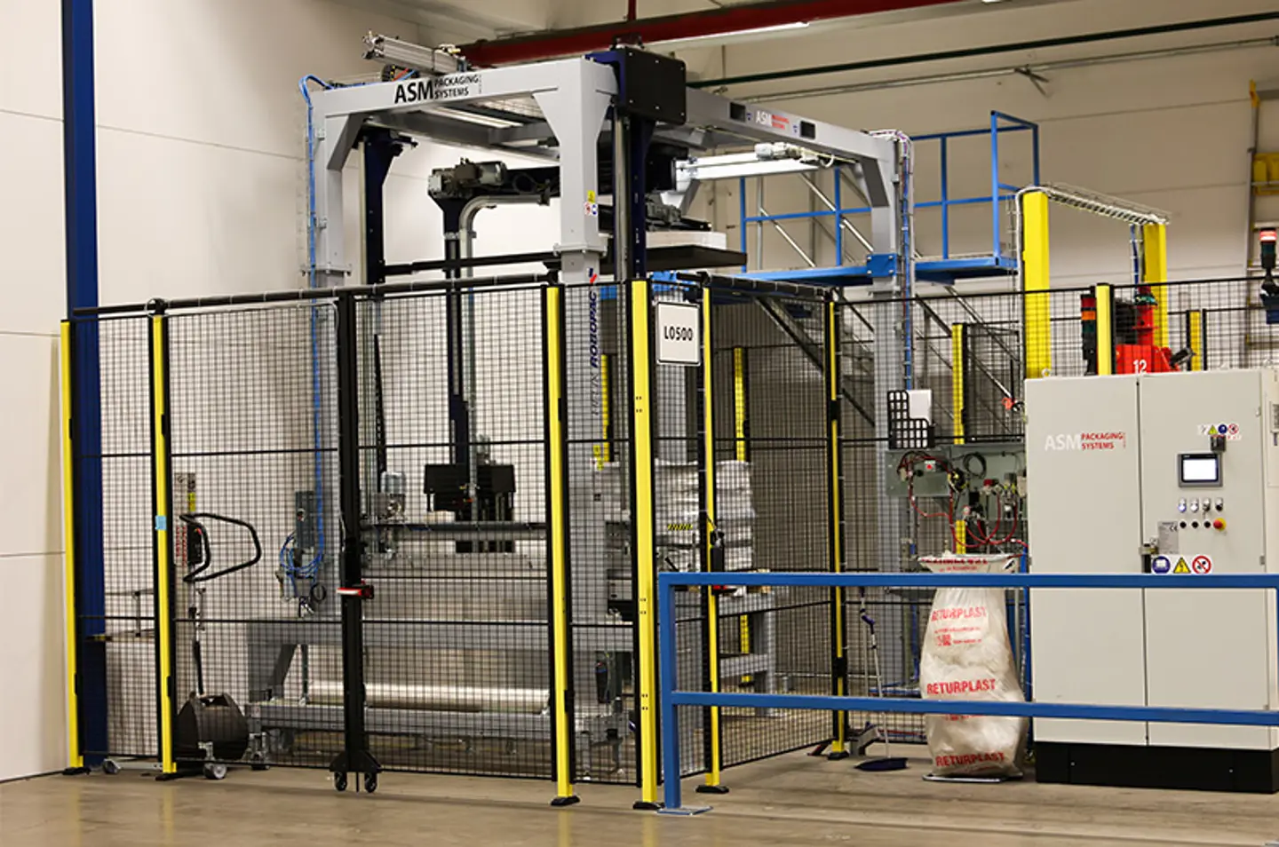 Automated packaging system in a warehouse, enclosed with safety fencing and equipped with control panels